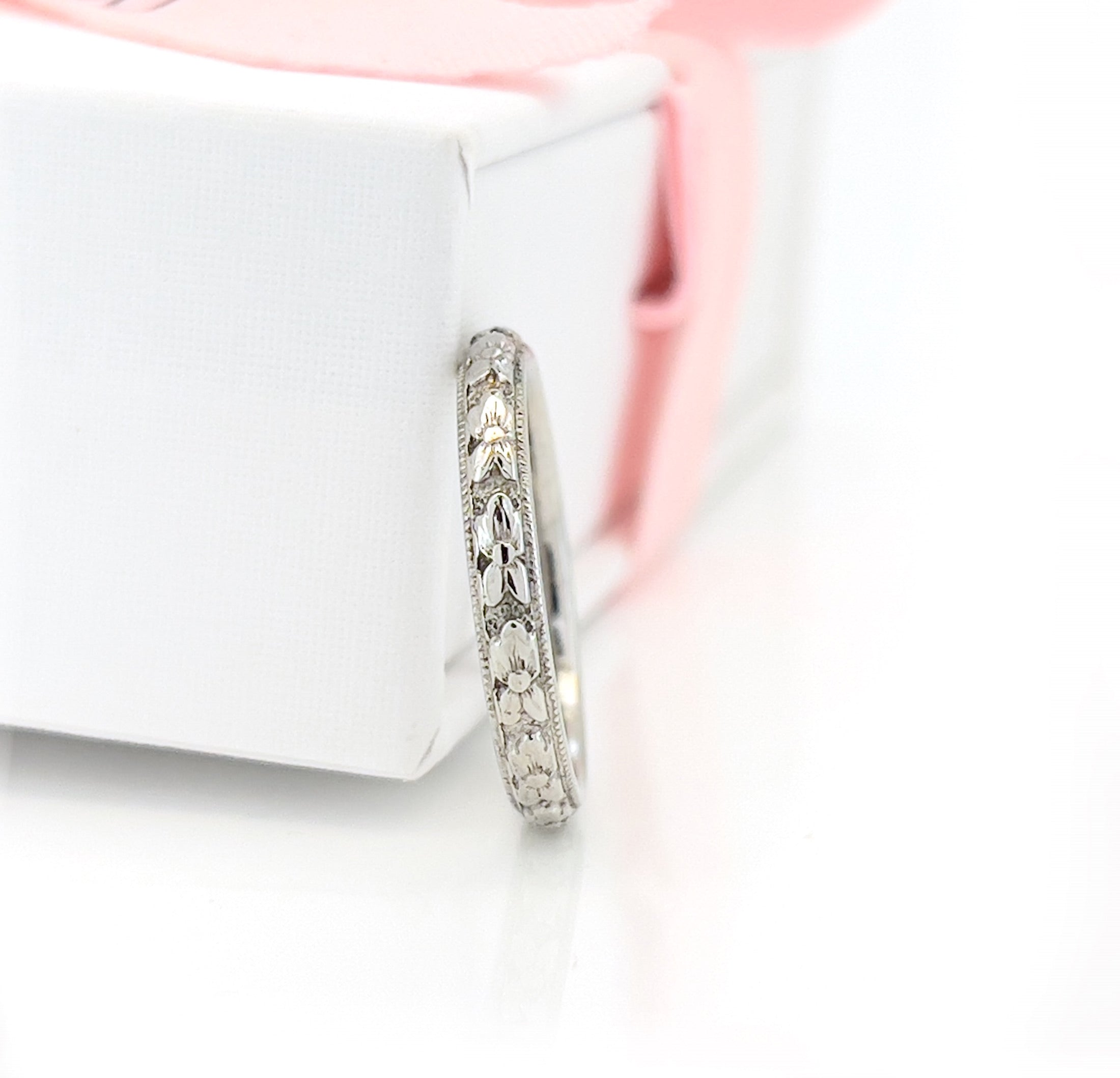 White gold ring with intricate design on a white surface