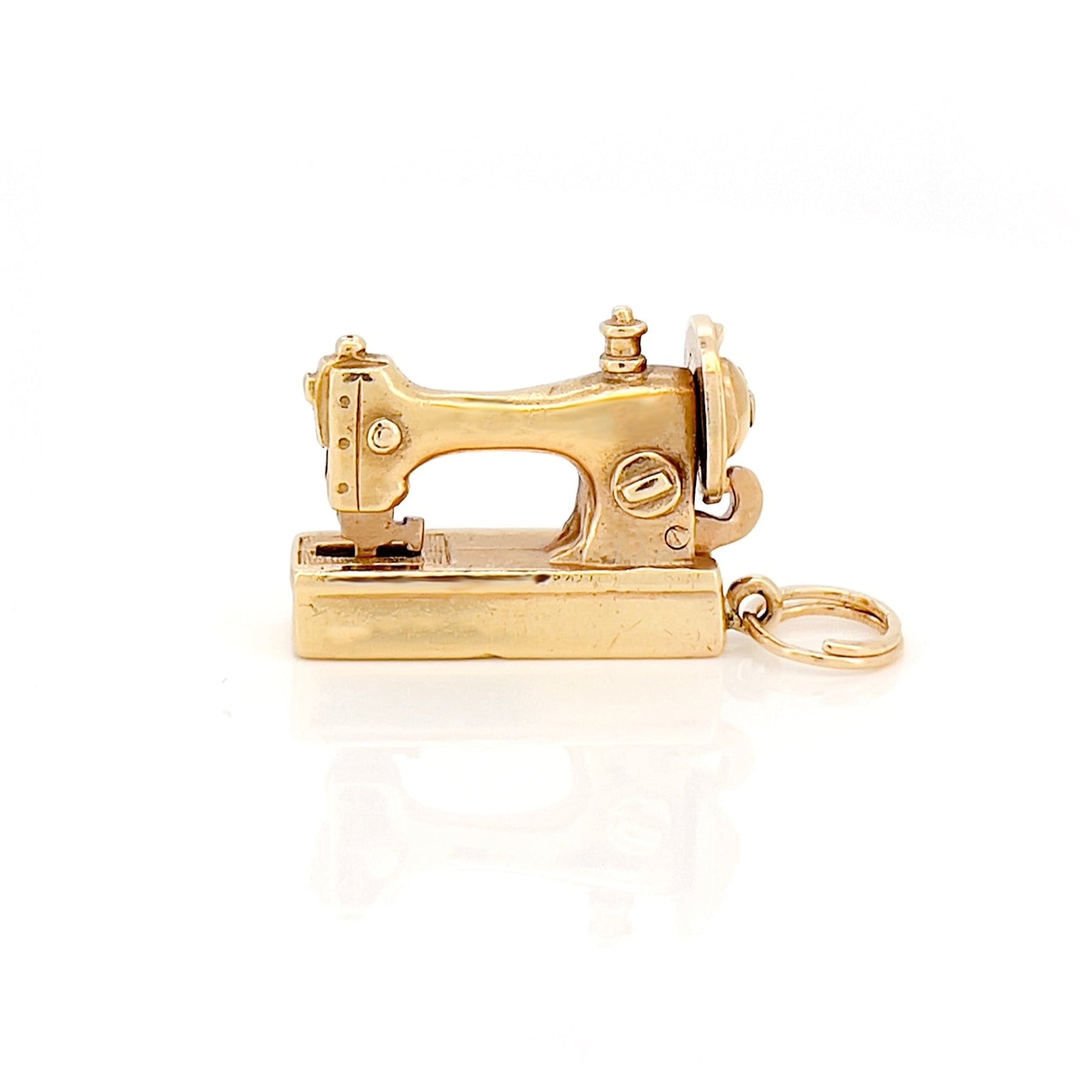 Gold sewing machine charm on a white background