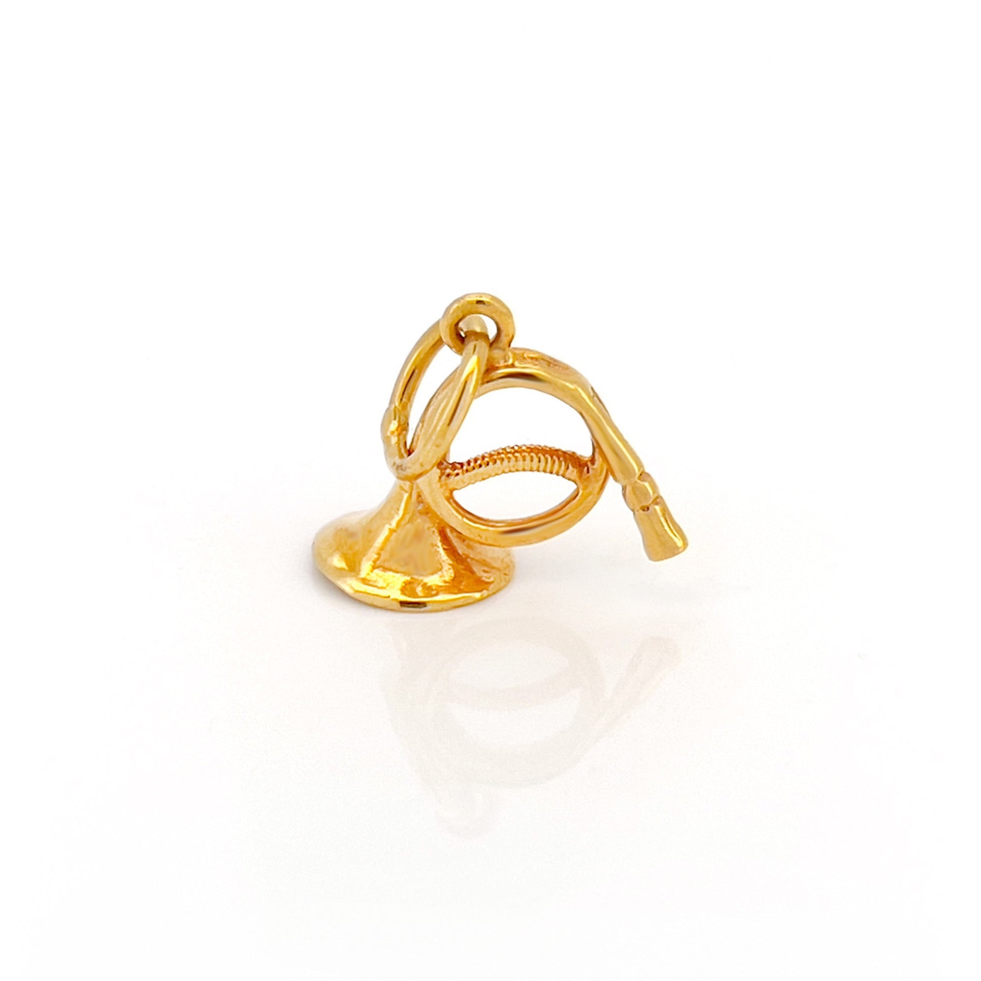Gold french horn charm on a white background