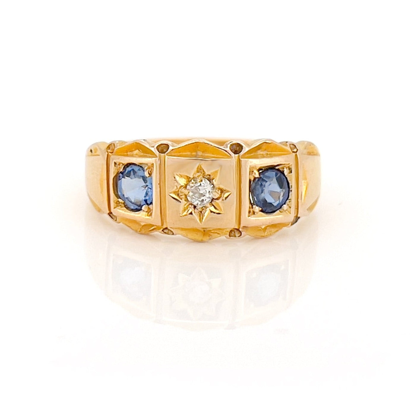 Gold ring with blue gemstones and a diamond on a white background