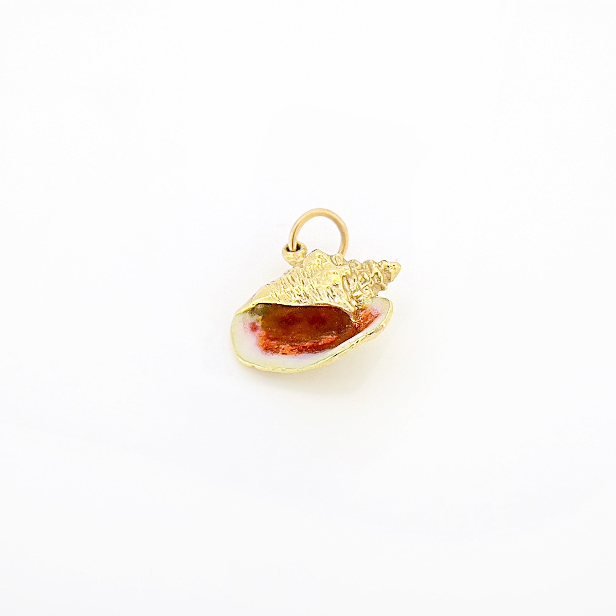 Gold shell pendant with a red stone on a white background