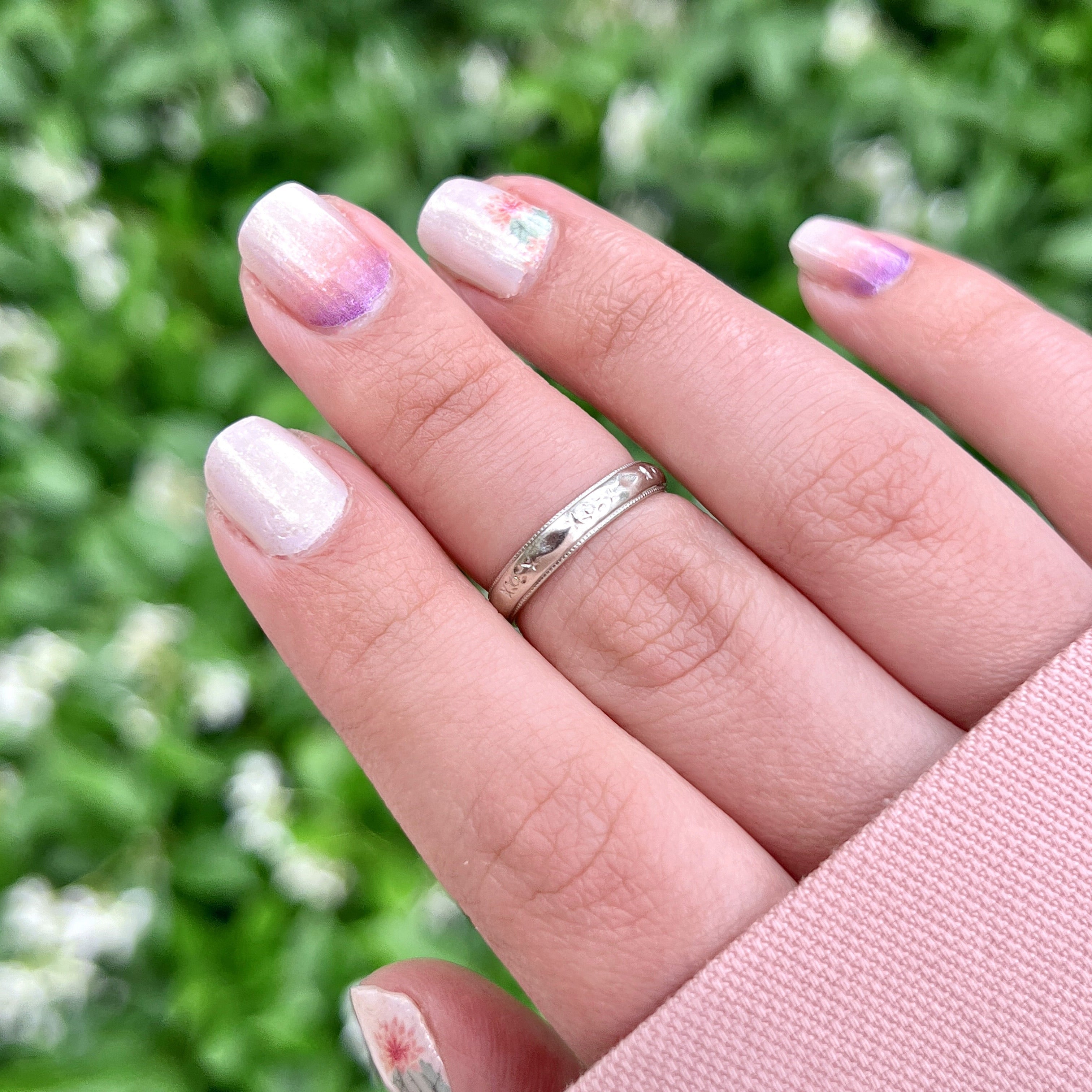 A person wearing a vintage white gold ring with faint orange blossom design and milgrain pattern, size 5.25, with an inscription.