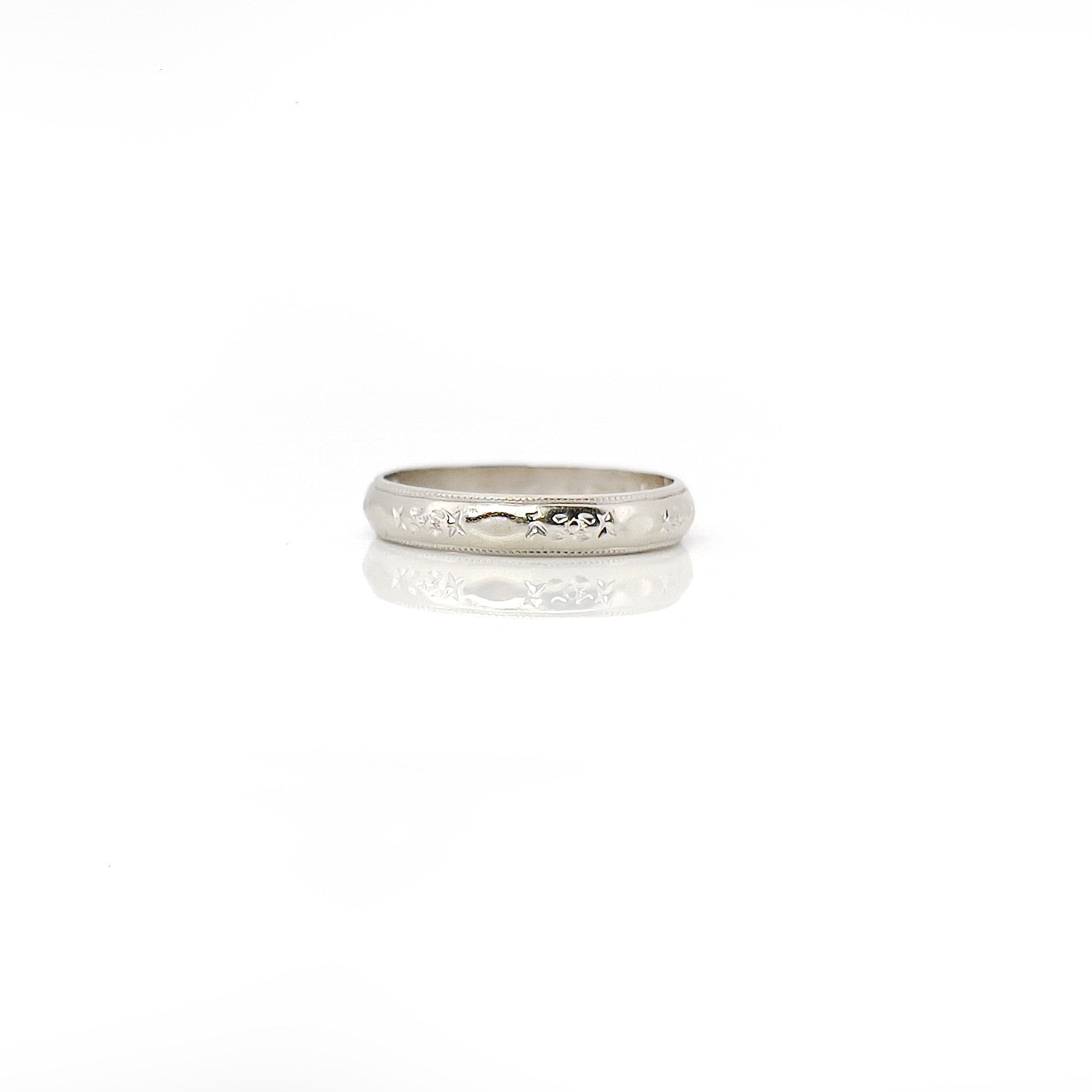 A vintage white gold ring with faint orange blossom design and milgrain pattern, size 5.25, with visible wear.