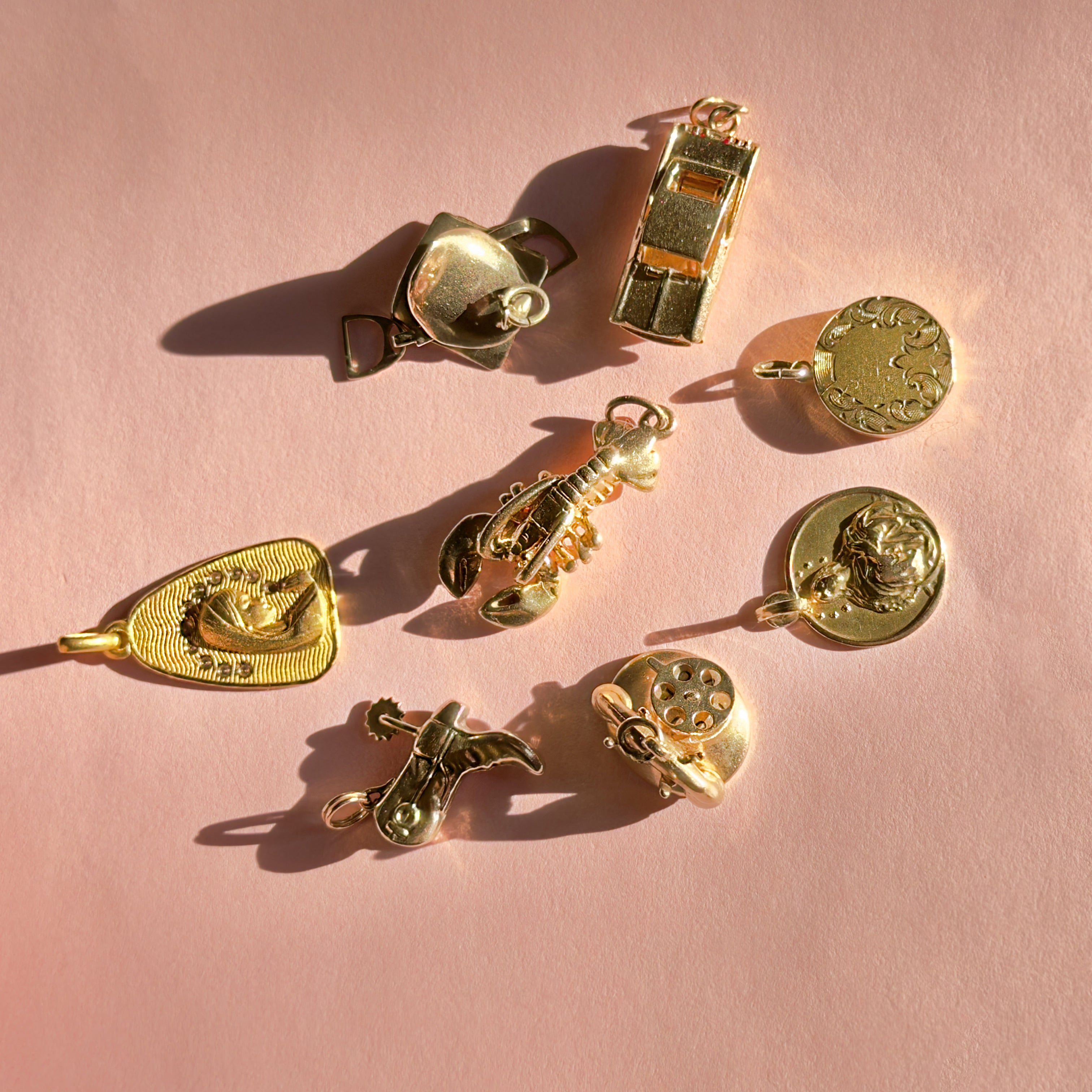 Gold jewelry charms on a pink background