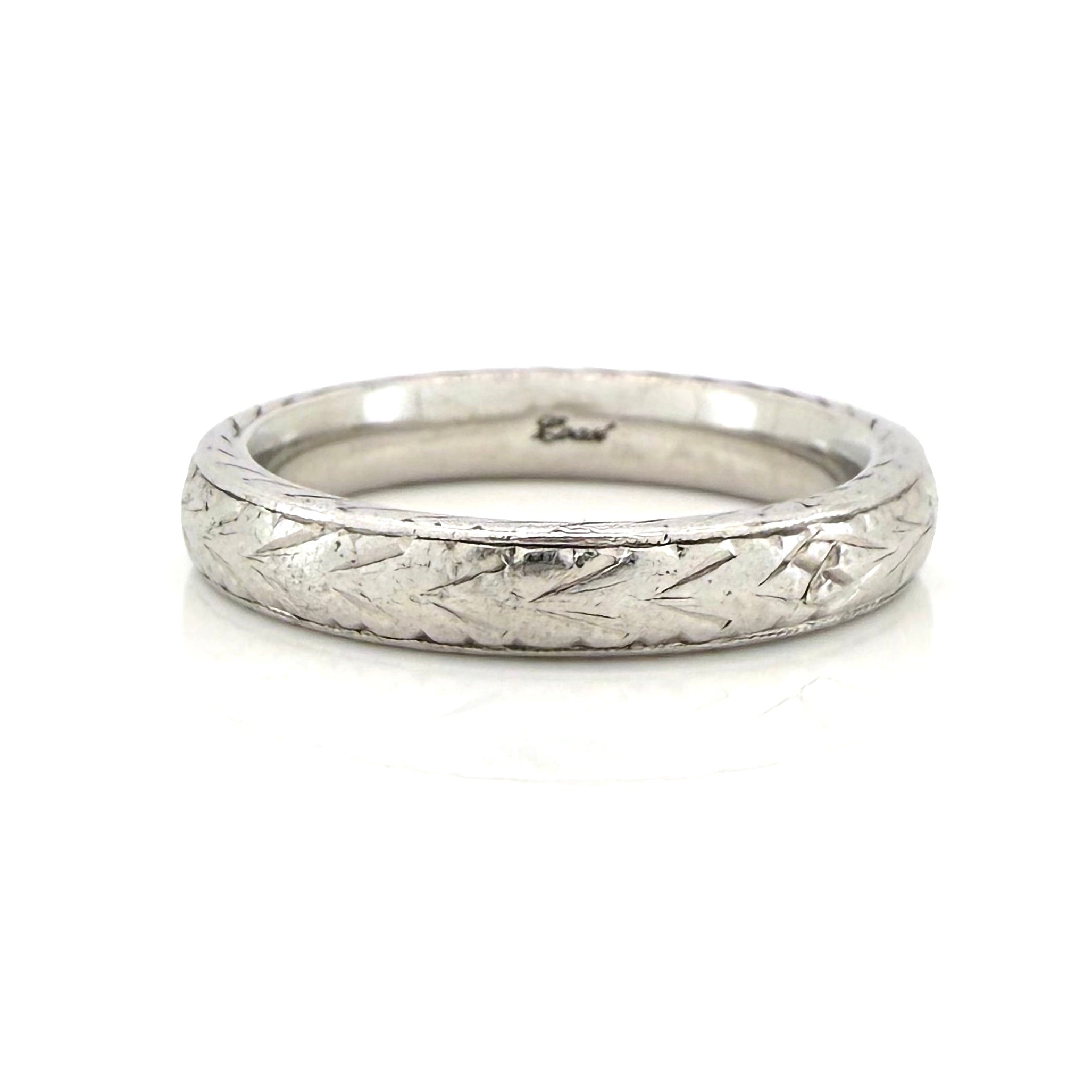 Vintage platinum ring with textured design on a white background