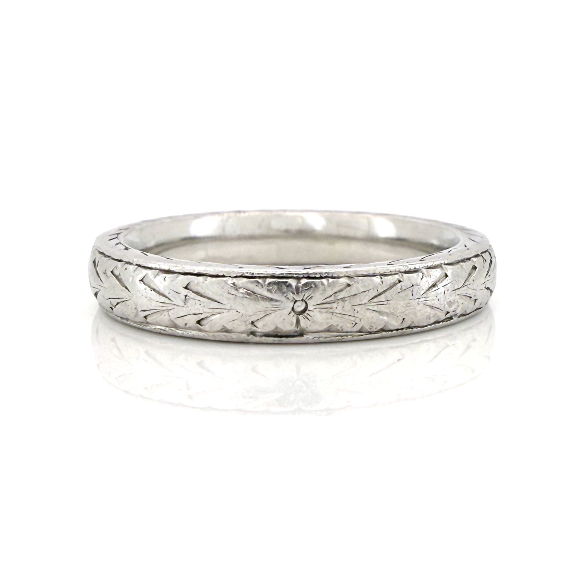 Vintage platinum ring with textured design on a white background