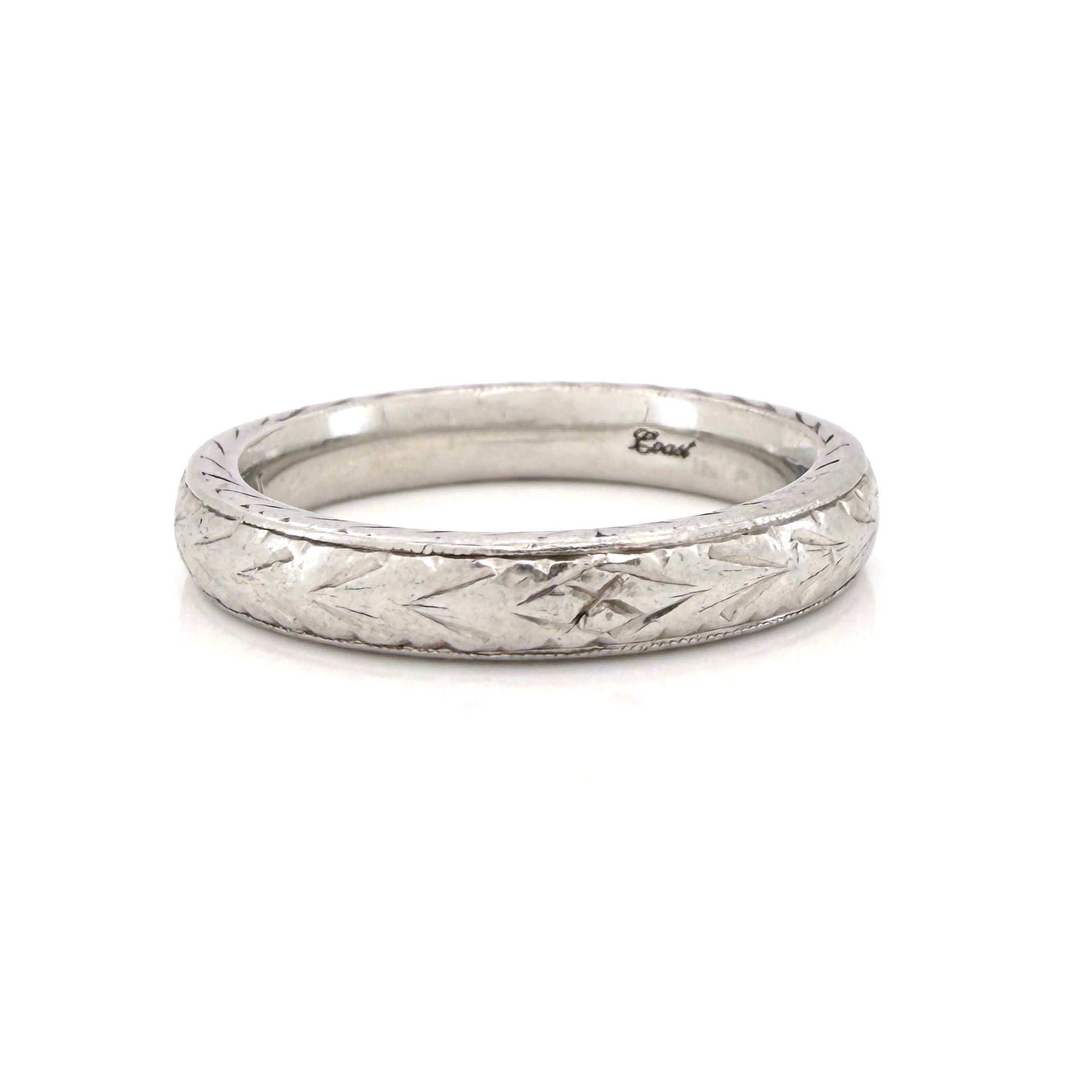 Vintage platinum ring with textured design on a white background