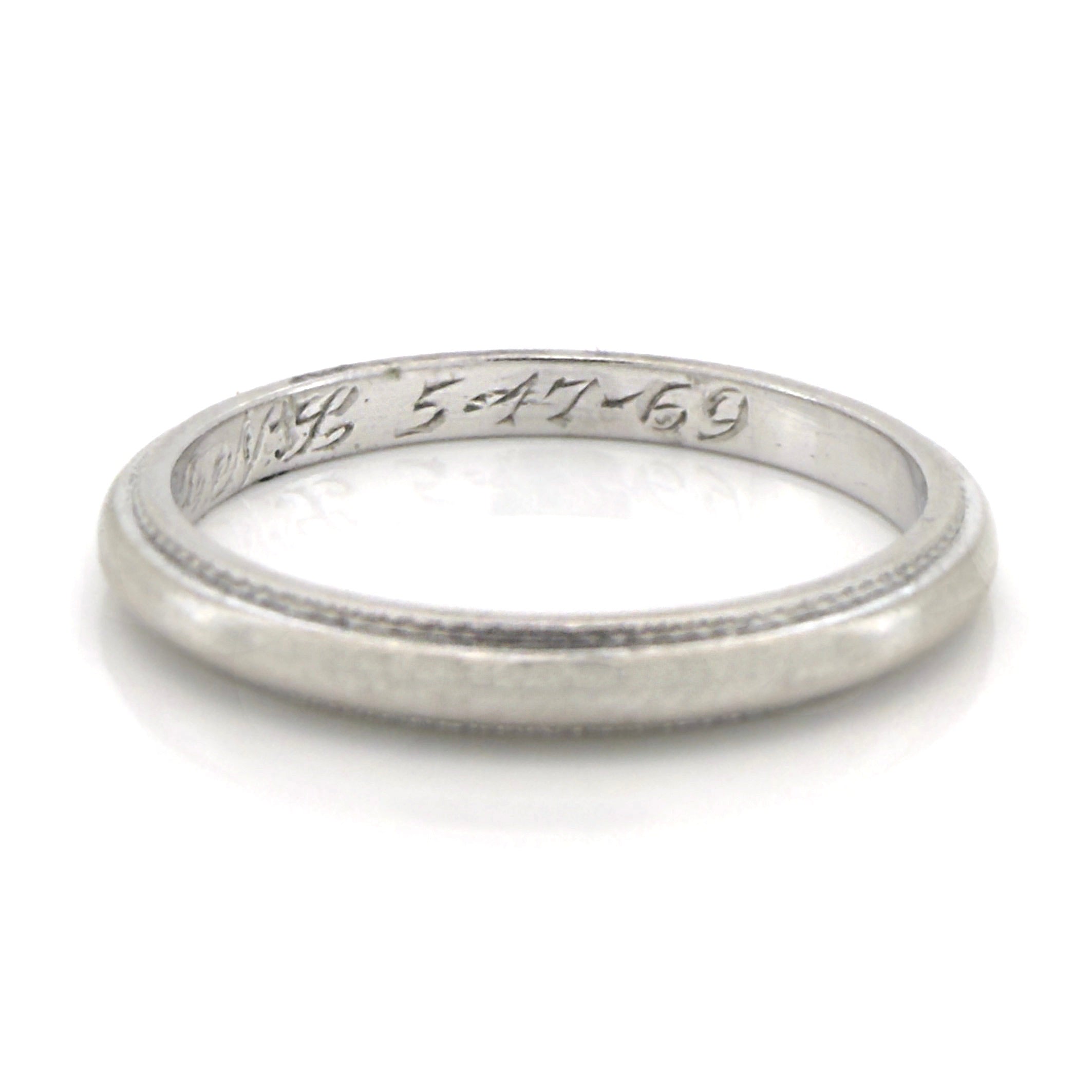 Vintage platinum ring with engraved text on a white background