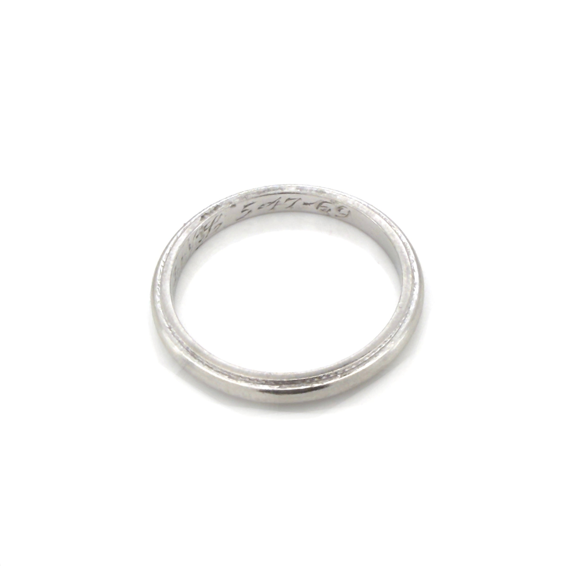 Vintage platinum ring with engraved text on a white background