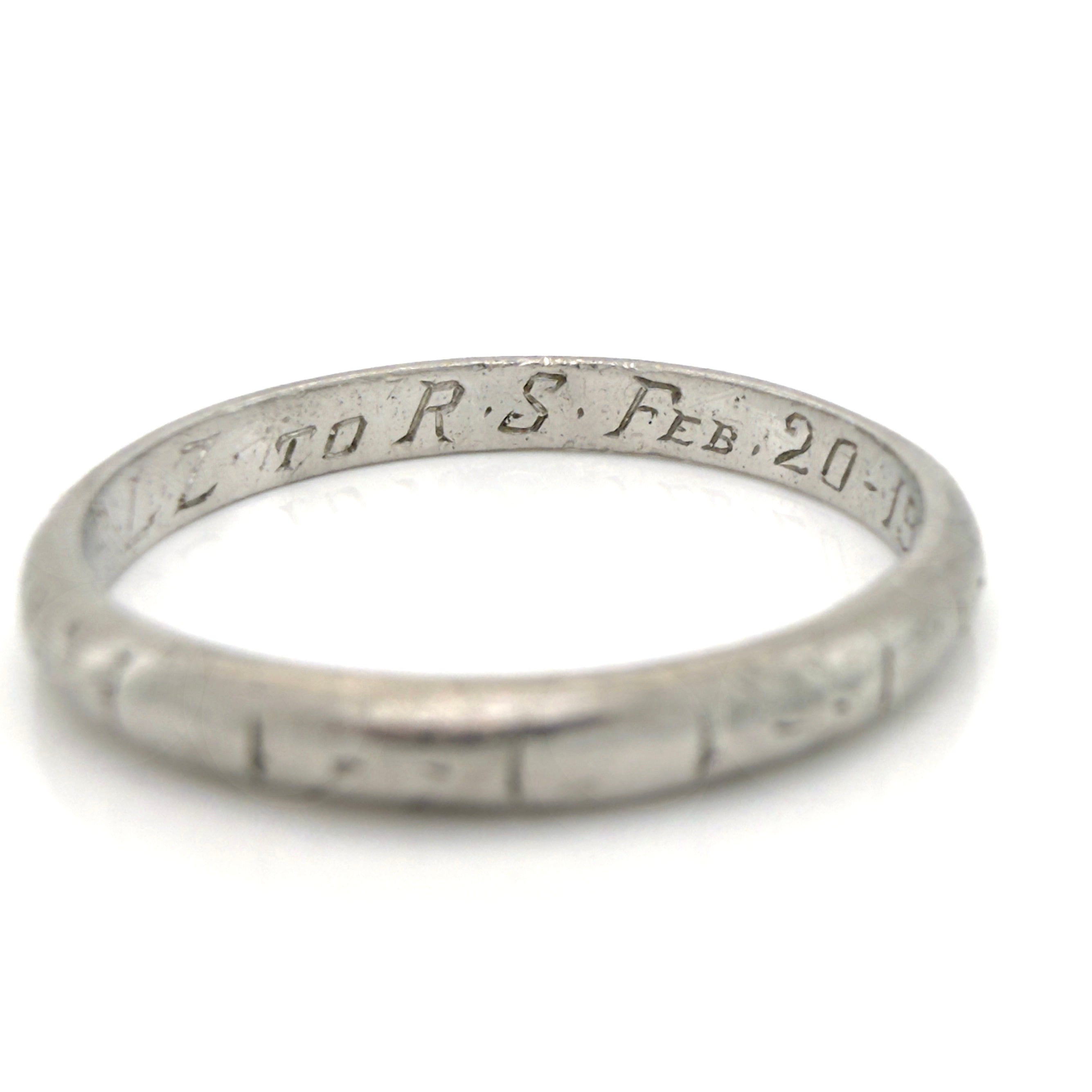 Art Deco platinum ring with engraved text on a white background
