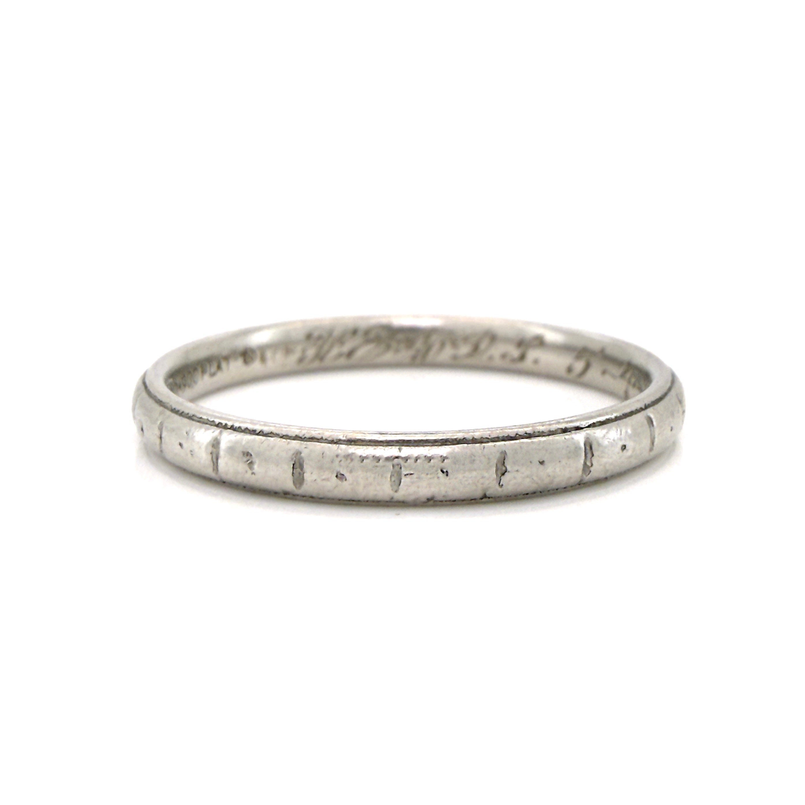 Antique platinum ring with engraved design on a white background