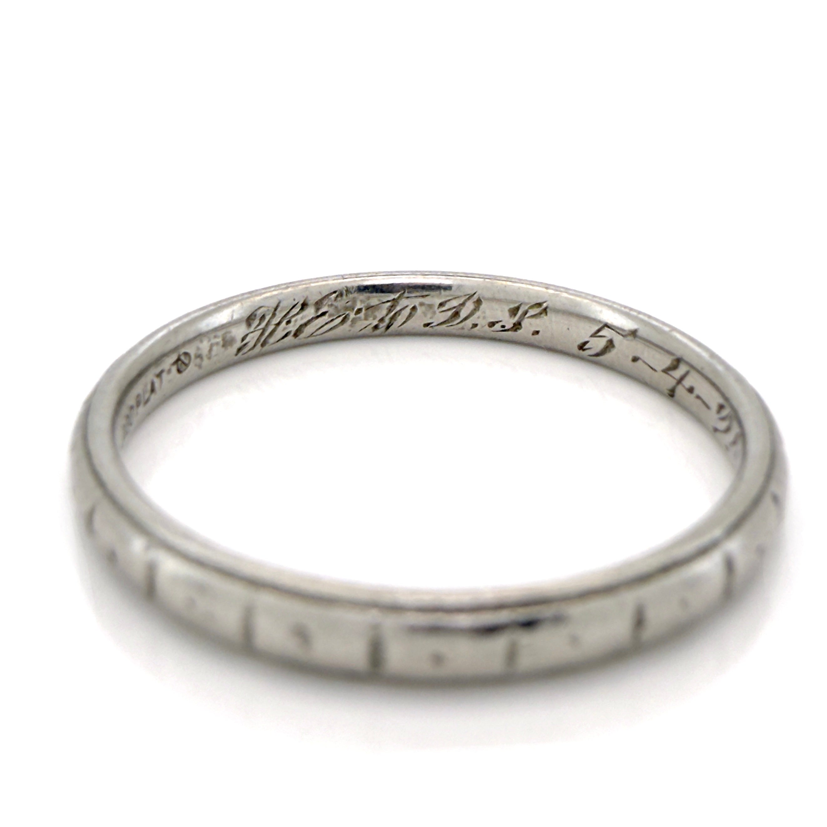 Antique platinum ring with engraved design on a white background