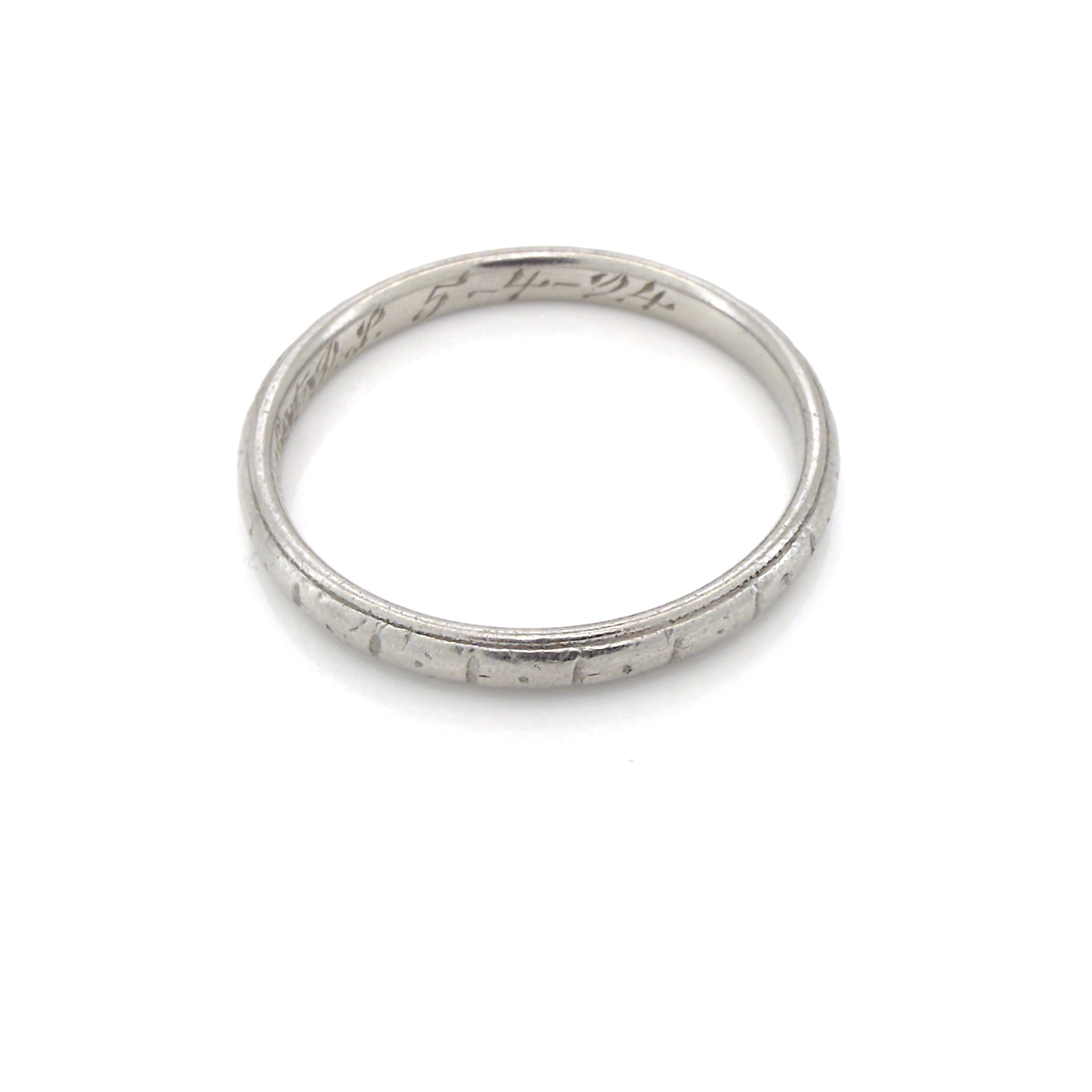 Antique platinum ring with engraved design on a white background