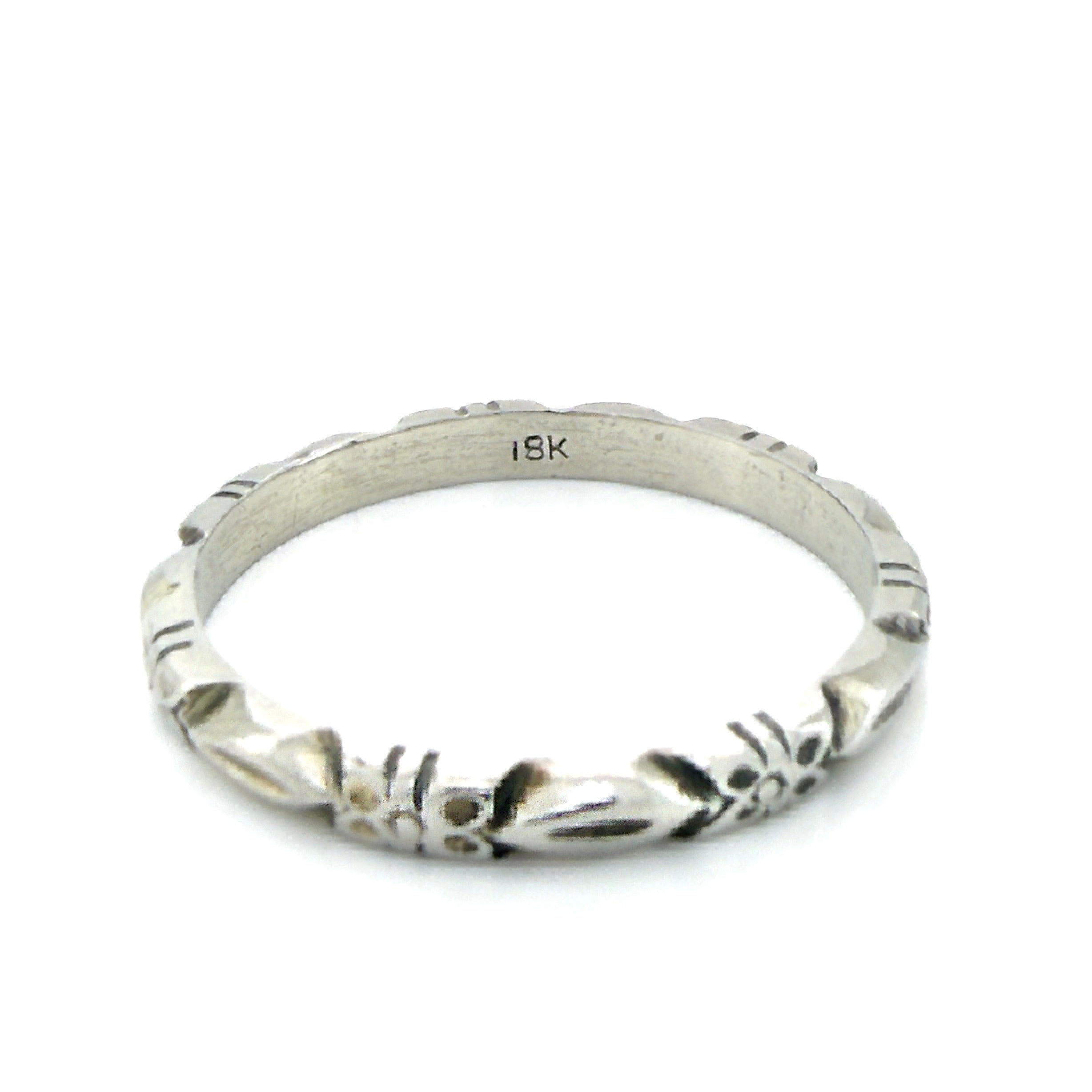 White gold ring with a flower pattern and an '18K' stamp on a white background