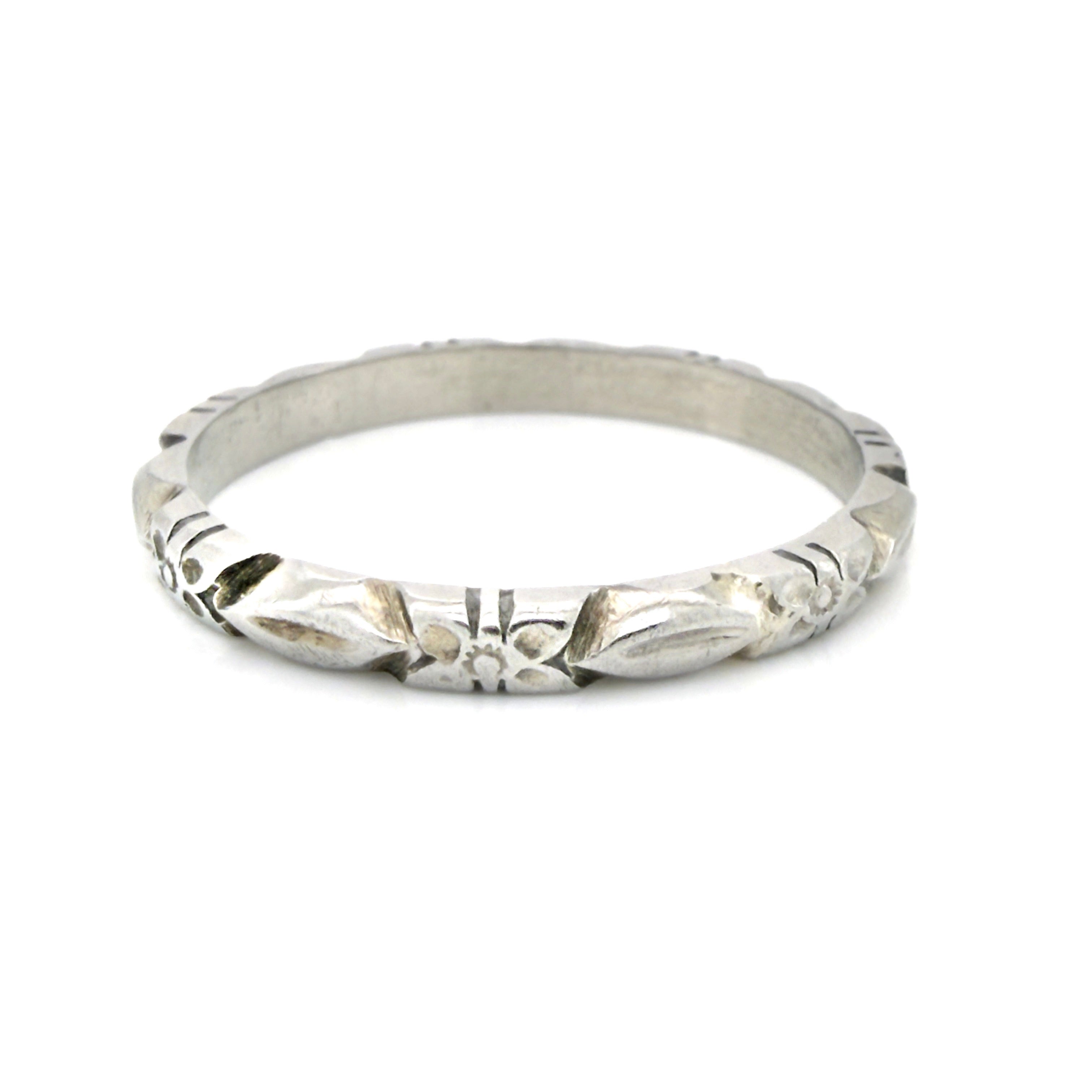 White gold ring with a flower pattern on a white background