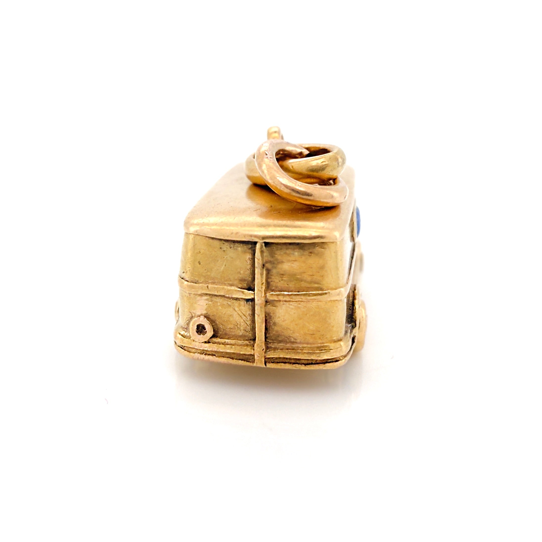 Rear end of a vintage gold microbus charm on a white background