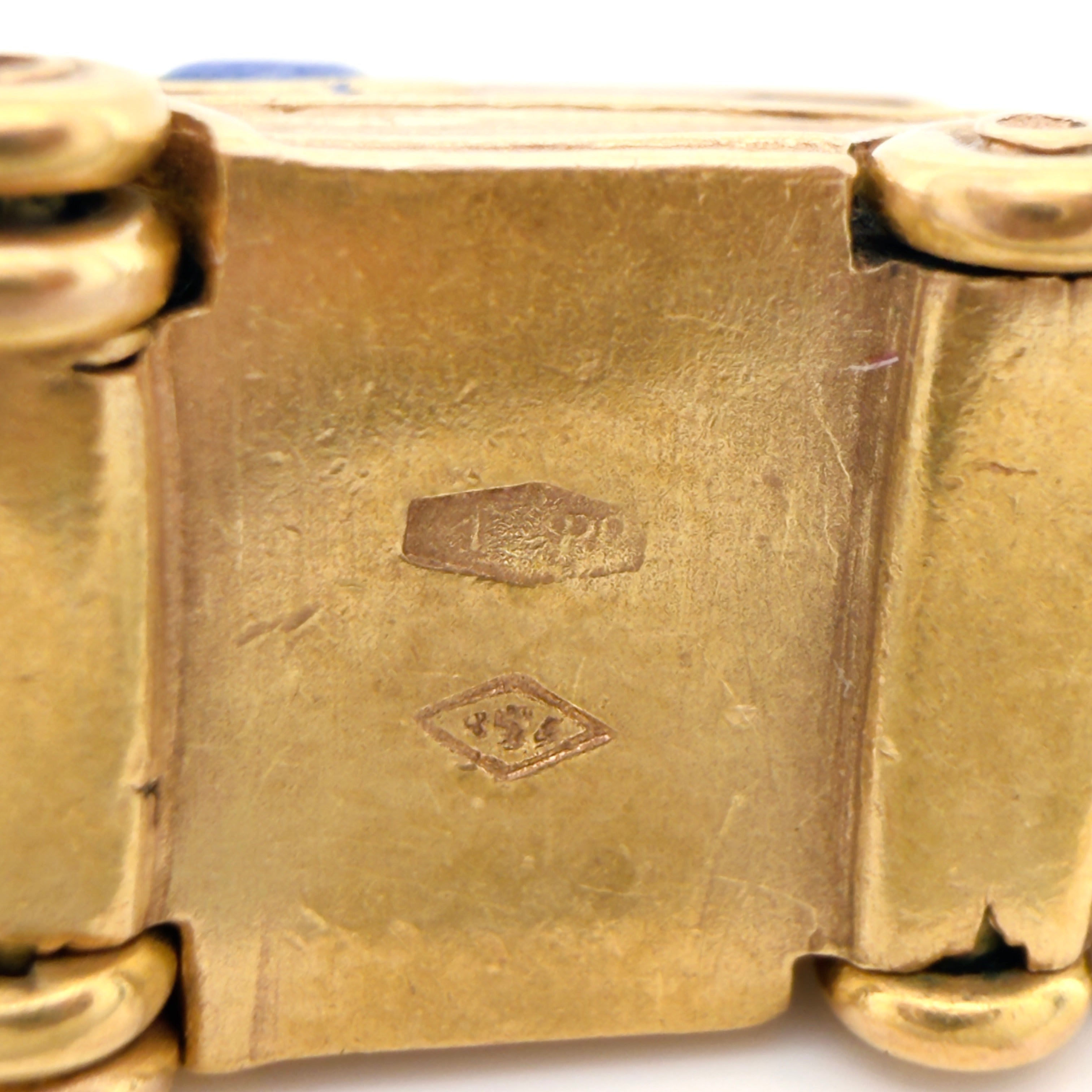 Bottom of a vintage gold microbus  charm with faint Italian hallmarks on a white background