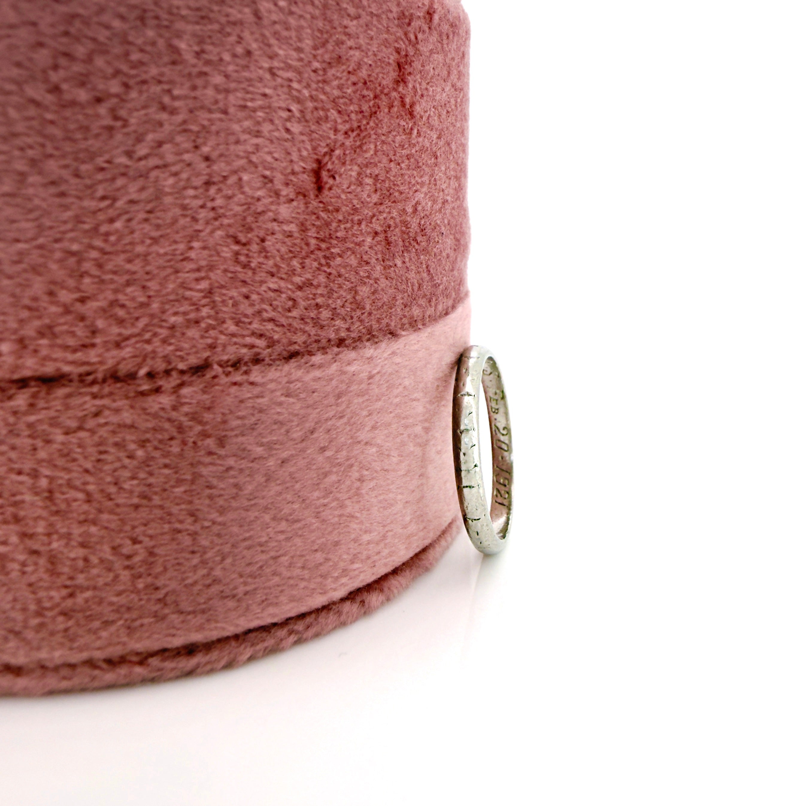 Close-up of a pink fabric ring box with a platinum ring on a white background