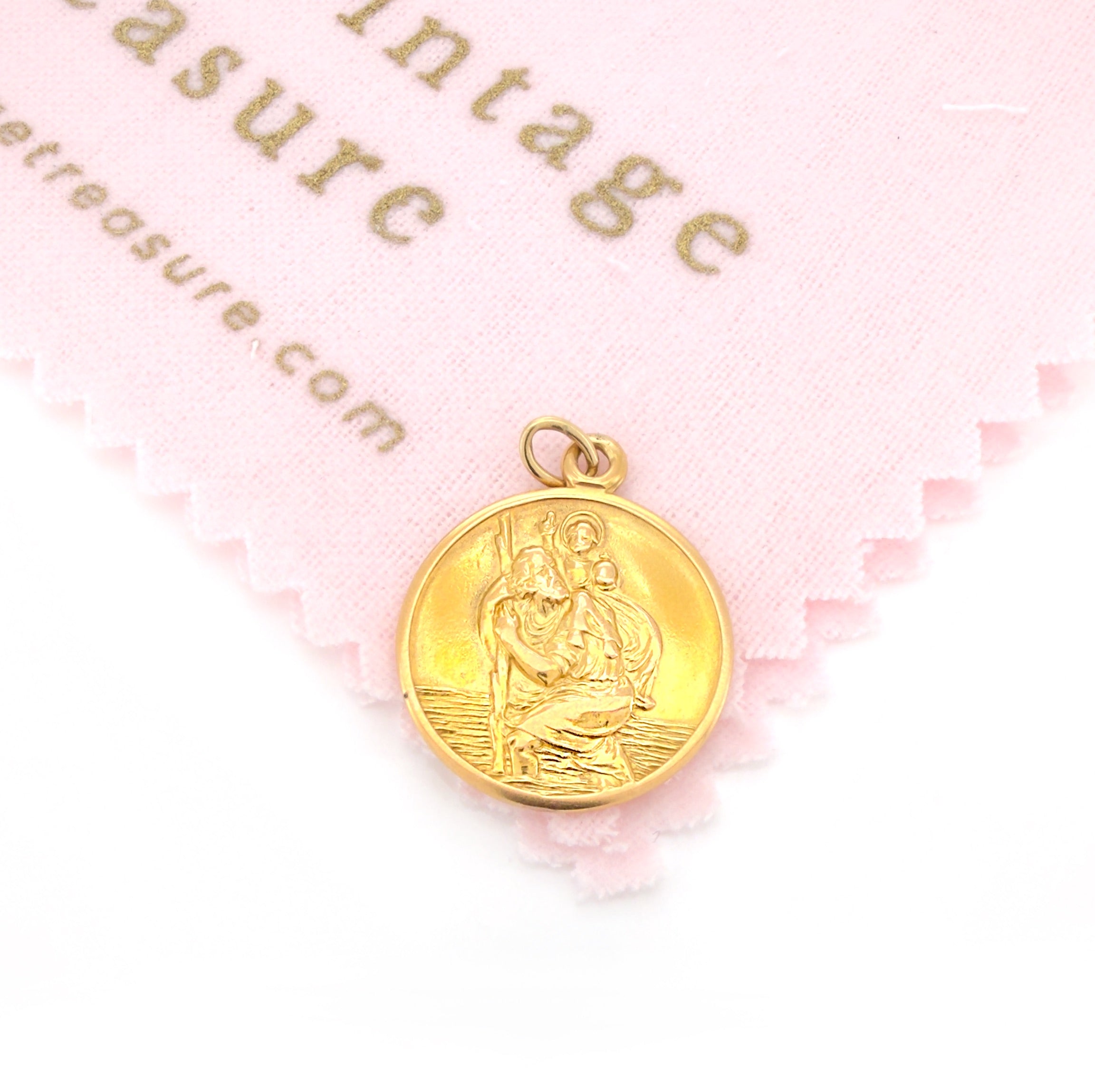Vintage gold pendant with religious design on a pink and white background