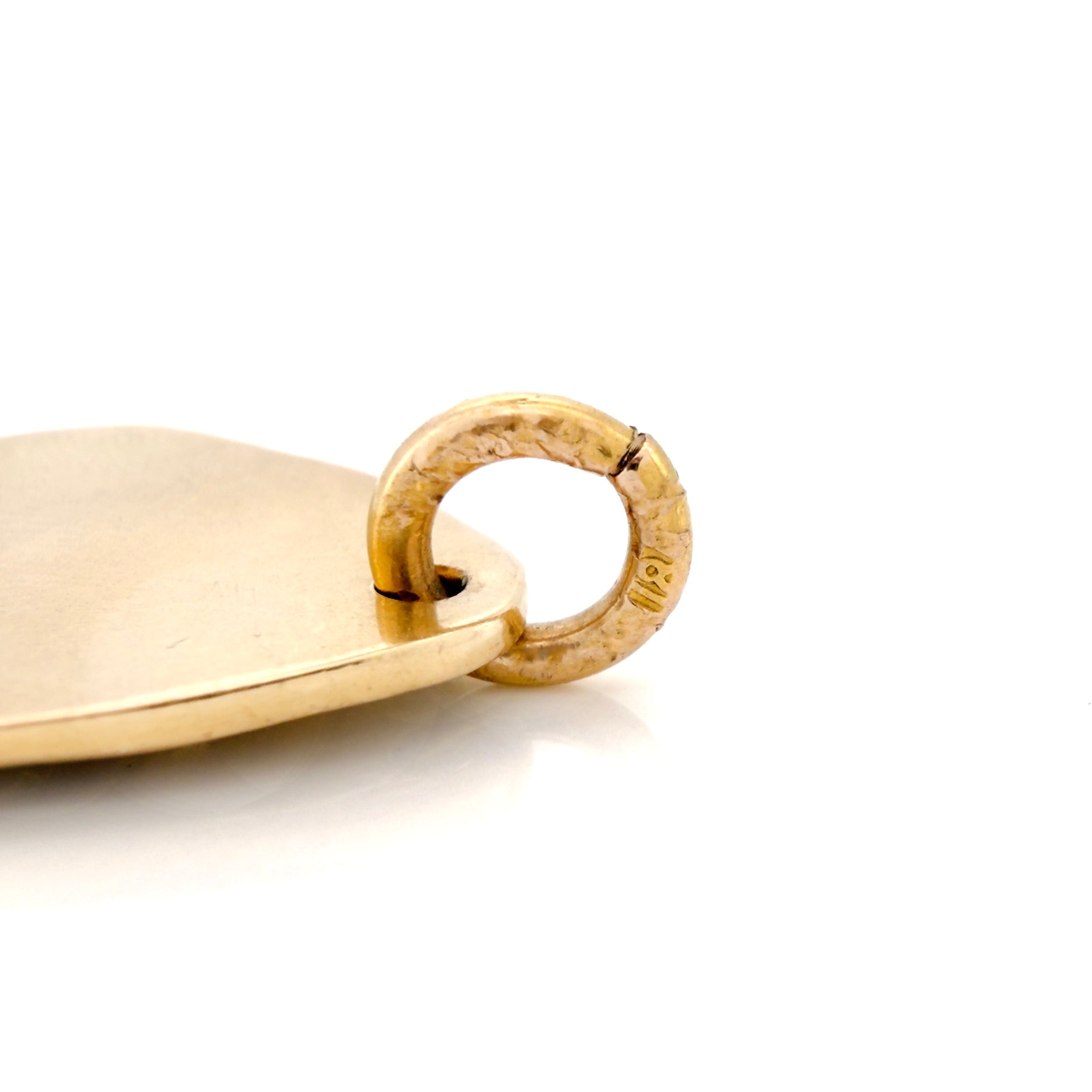 Gold pendant with a circular bail on a white background