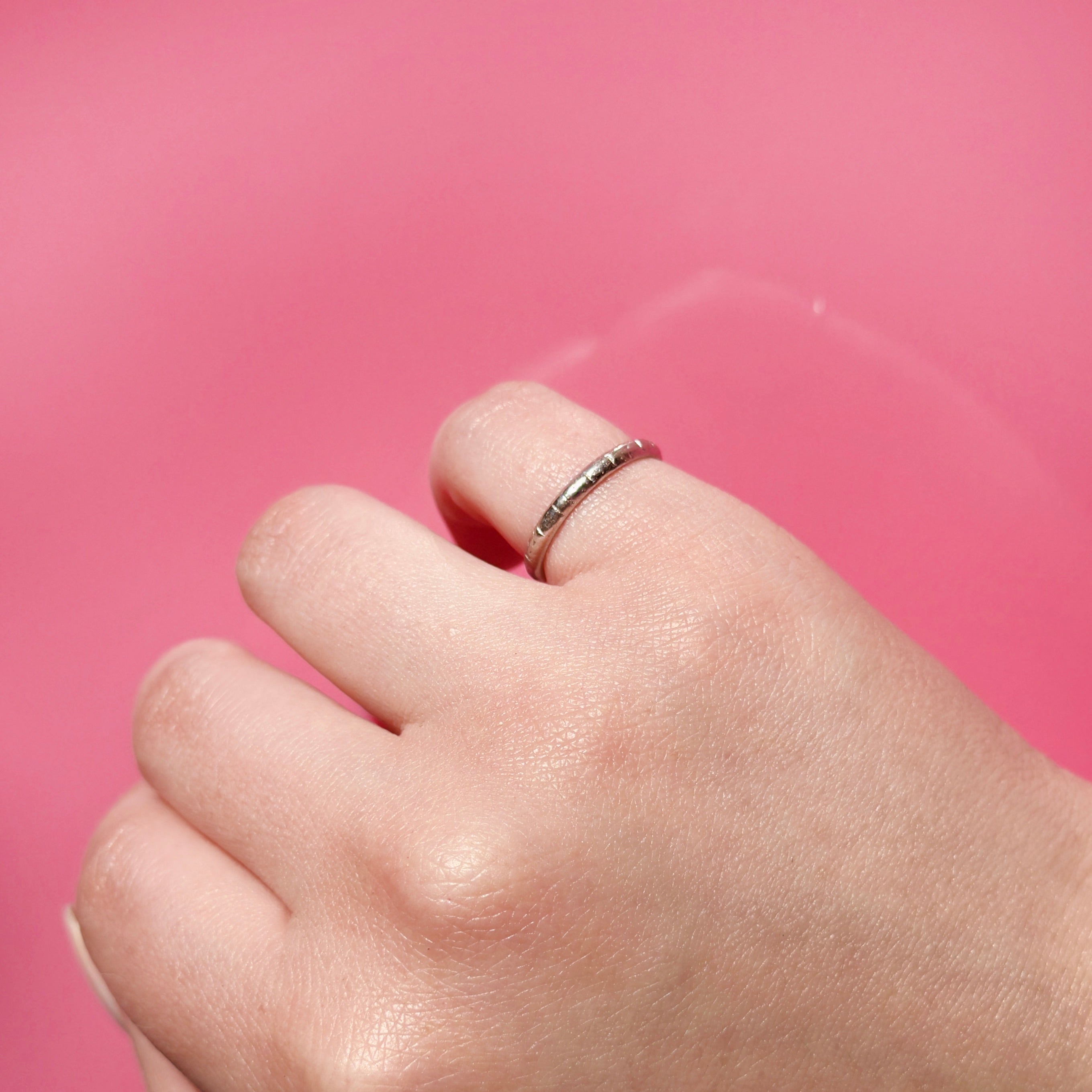 Hand wearing an Art Deco Platinum ring on a pink background