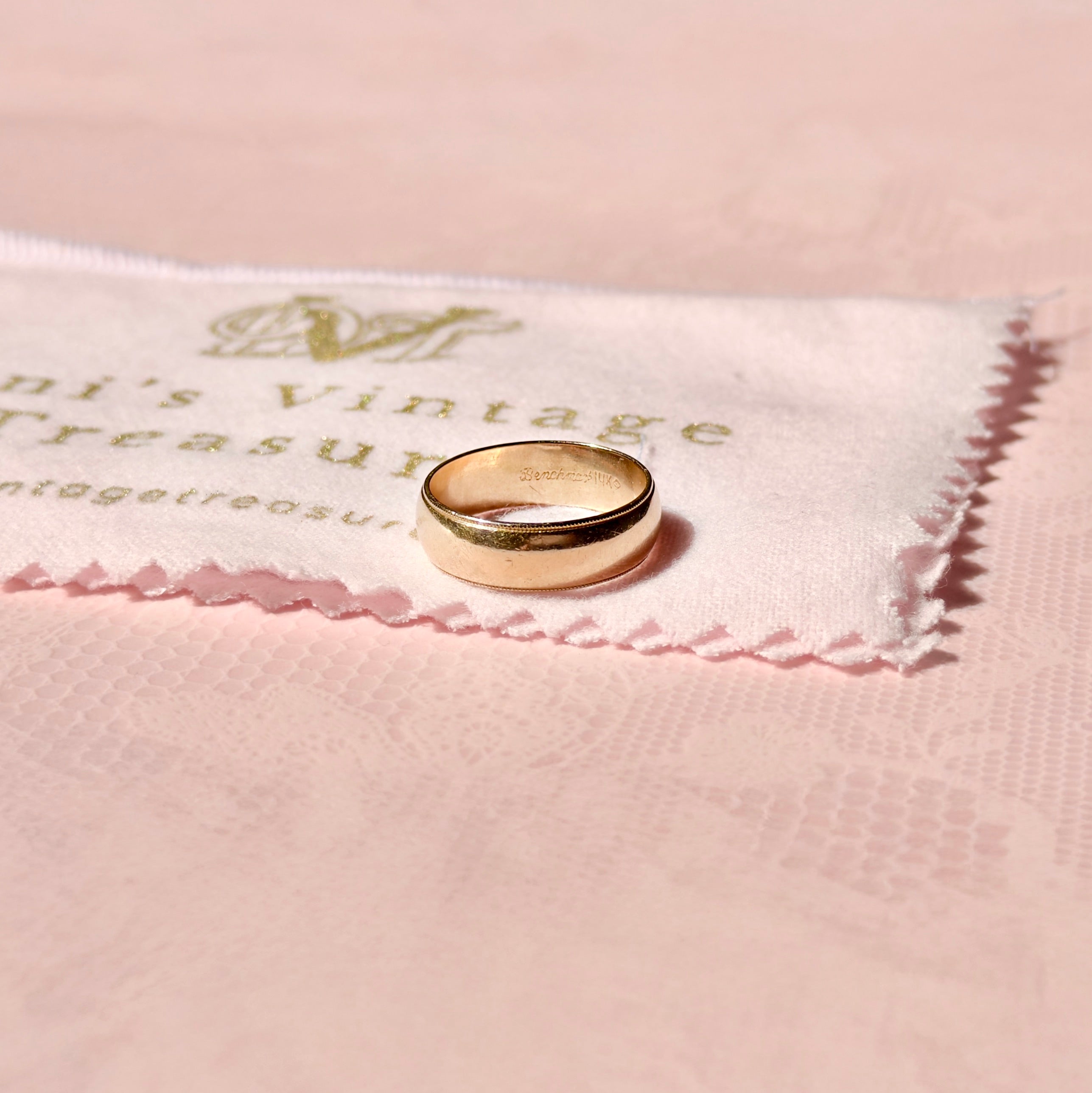 Gold ring on a pink cloth with 'Vintage Treasure' branding