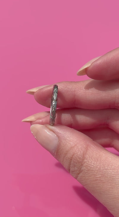Two fingers holding a vintage white gold ring