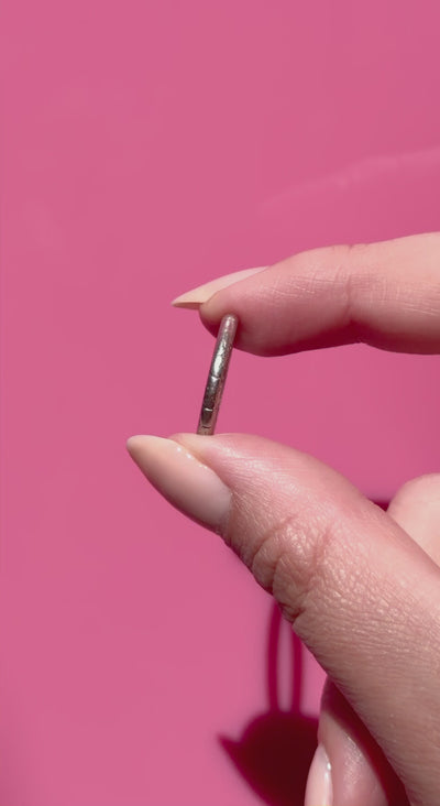 Hand holding an antique platinum ring against a pink background